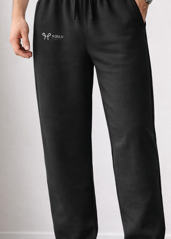 Person wearing black sweatpants with a logo on a plain background